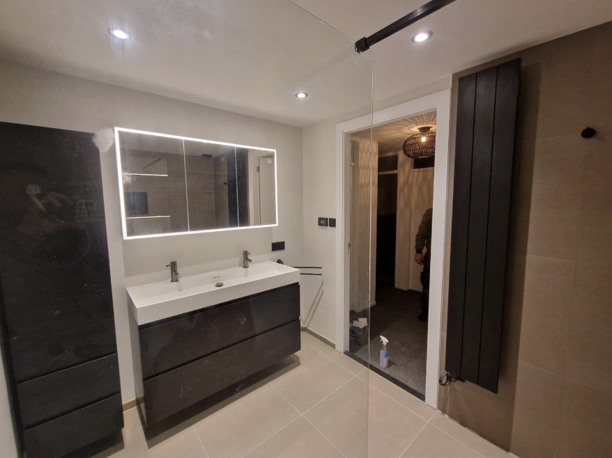 Moderne badkamer met verlichte spiegelkast en donker meubel